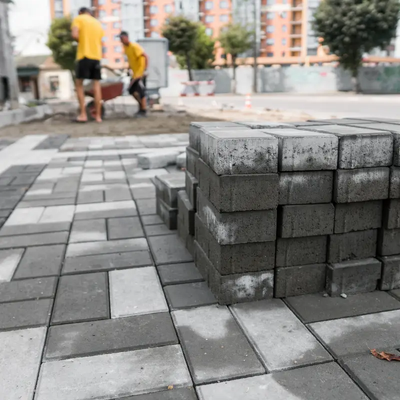 Driveway and Paving Services Woodbridge team laying paving blocks for a business courtyard.